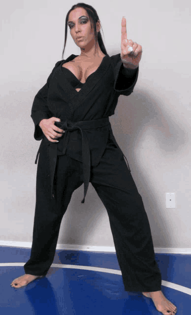 a woman in a black karate uniform points her finger
