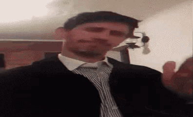 a man in a suit and tie is standing in a room .