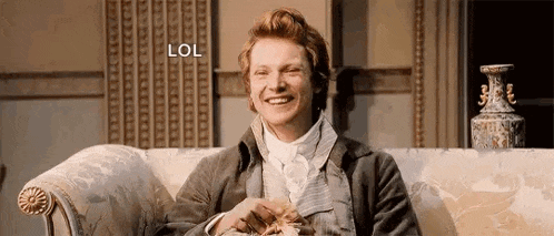 a man in a suit is sitting on a couch eating popcorn and laughing .