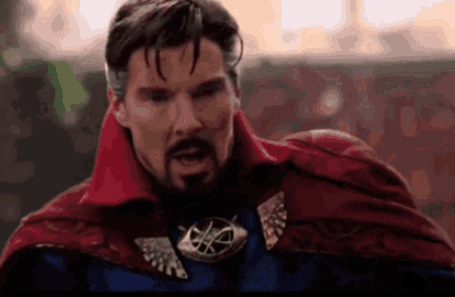 a close up of a man with a beard wearing a red cape and a necklace .