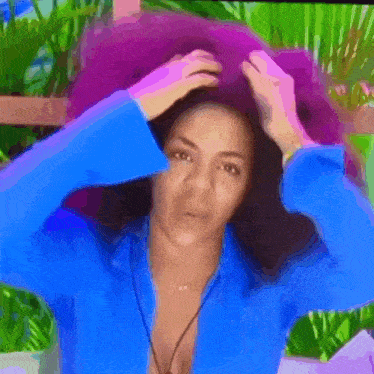a woman in a blue shirt is scratching her head with her hands