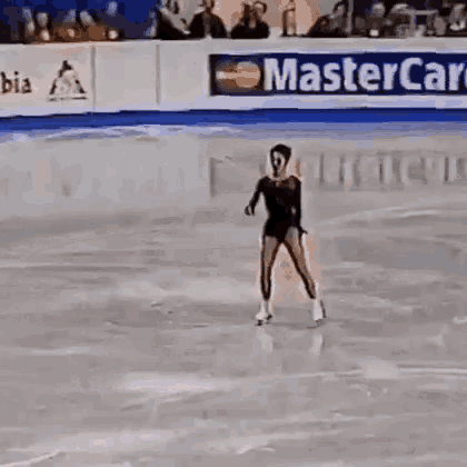 a woman is ice skating in front of a mastercard sign .