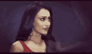 a woman with long dark hair is wearing a red tank top