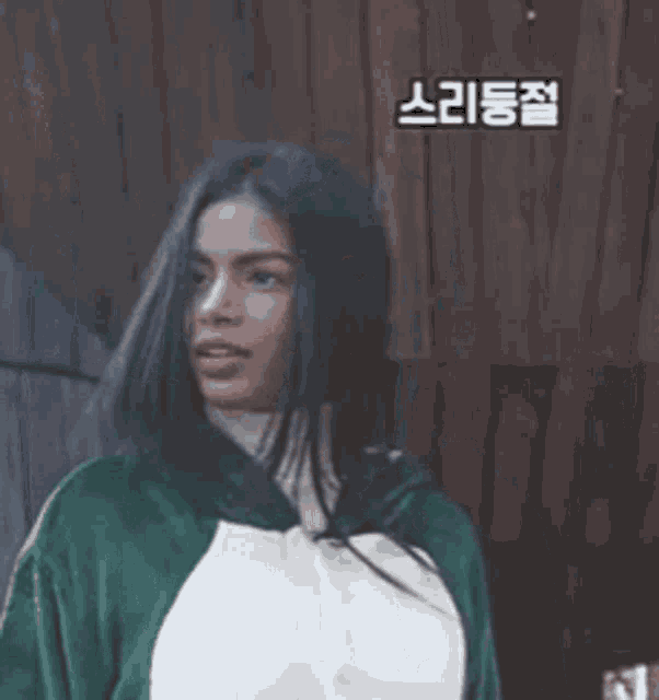 a woman with long black hair is wearing a green and white jacket .