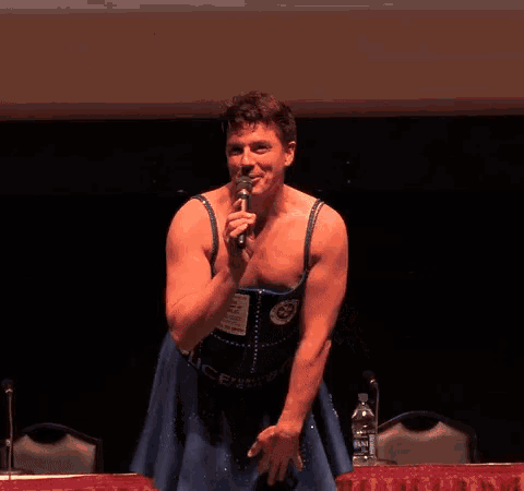 a man in a blue dress is singing into a microphone and has the word police on his belt