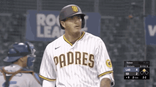 a padres baseball player stands in front of a sign that says rock lea