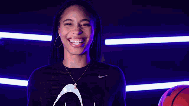 a woman is smiling while holding a basketball in her hand .