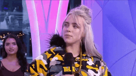 billie eilish is wearing a yellow and black camouflage jacket