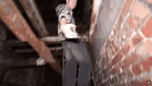 a blurry picture of a person standing next to a brick wall with a x in the corner .