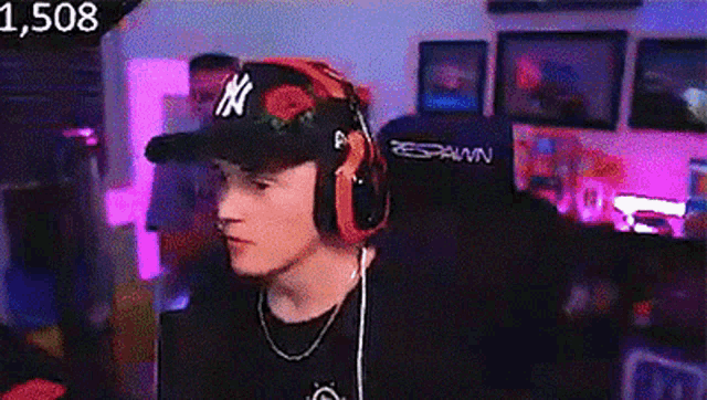 a young man wearing a hat and headphones is sitting in a chair .
