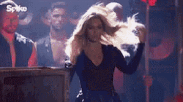 a woman is dancing on a stage in front of a crowd .
