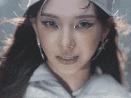 a close up of a woman 's face wearing a white hat and earrings .