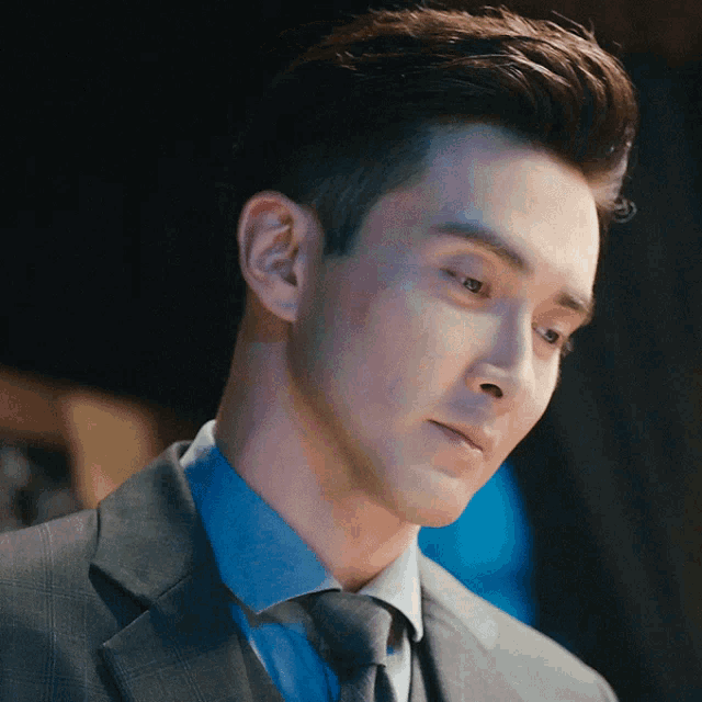 a man in a suit and tie looks to his left