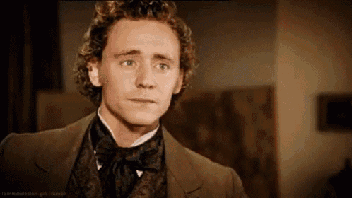 a man with curly hair is wearing a suit and tie and making a funny face .