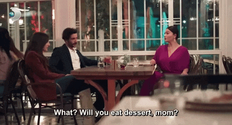 a woman in a purple dress is sitting at a table talking to a man in a suit