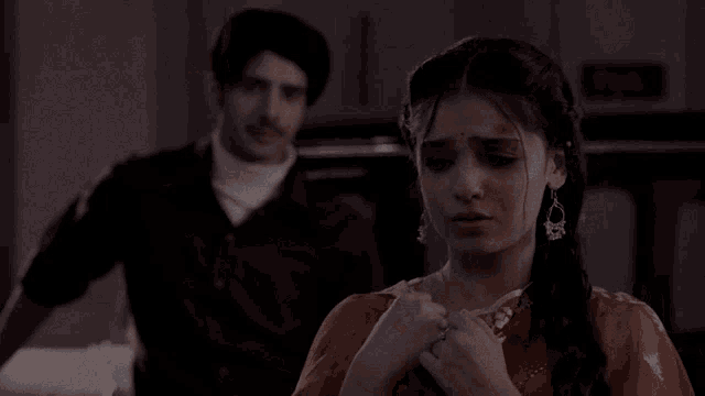 a man stands behind a woman who is crying