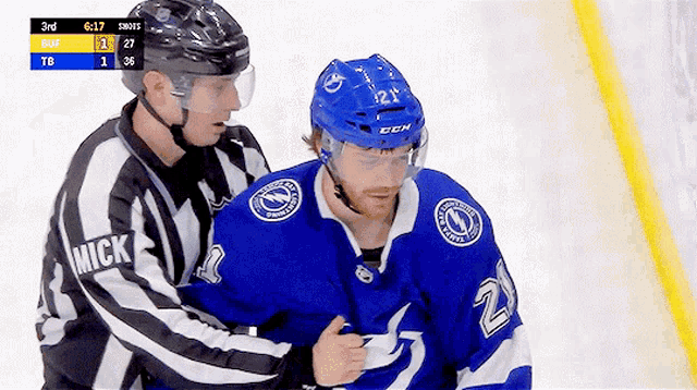 a hockey player with the number 21 on his jersey is being helped by a referee