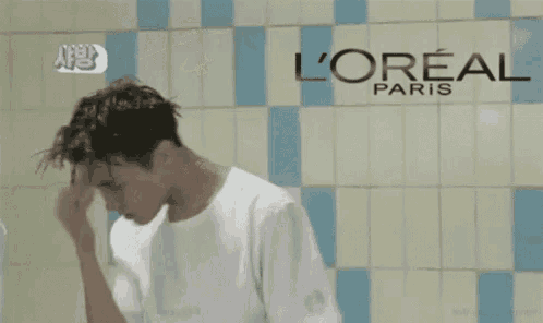 a man is washing his hair in front of a l' oreal paris advertisement .