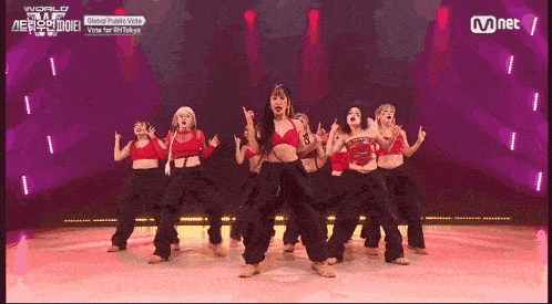 a group of women are dancing on a stage with mnet written on the bottom of the screen