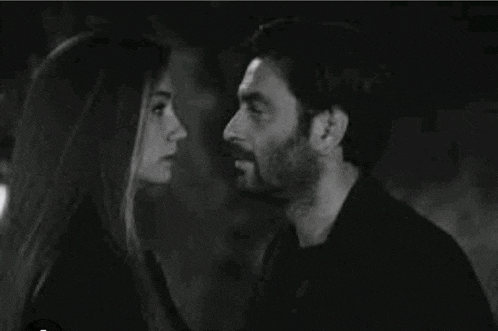 a black and white photo of a man and woman kissing .