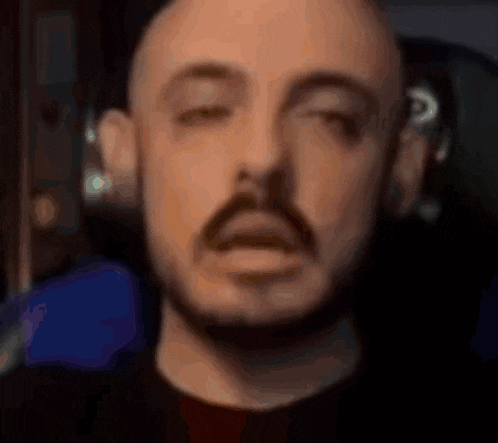 a bald man with a beard is making a funny face with his eyes closed