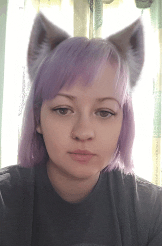 a girl with purple hair and cat ears looks at the camera