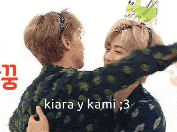 two men are hugging each other with a frog on their head .