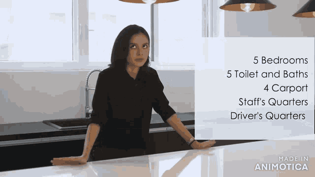 a woman stands in a kitchen with a sign that says 5 bedrooms 5 toilet and baths