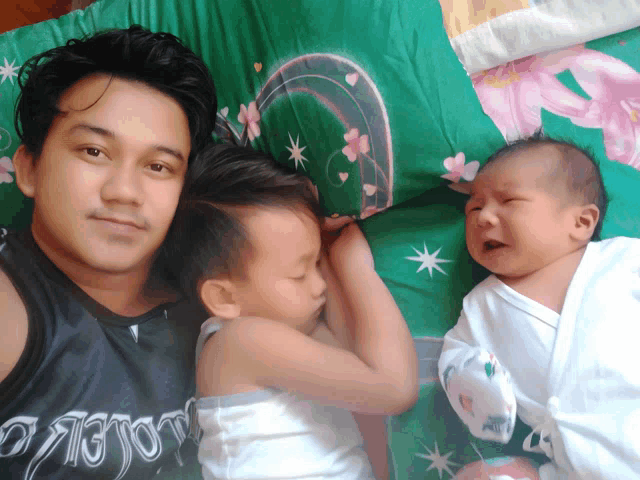 a man laying on a bed with two children one of whom is wearing a shirt that says ' warrior '