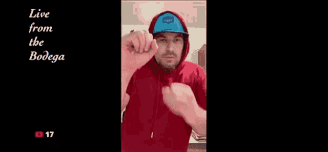 a man wearing a red hoodie and a hat is making a funny face .