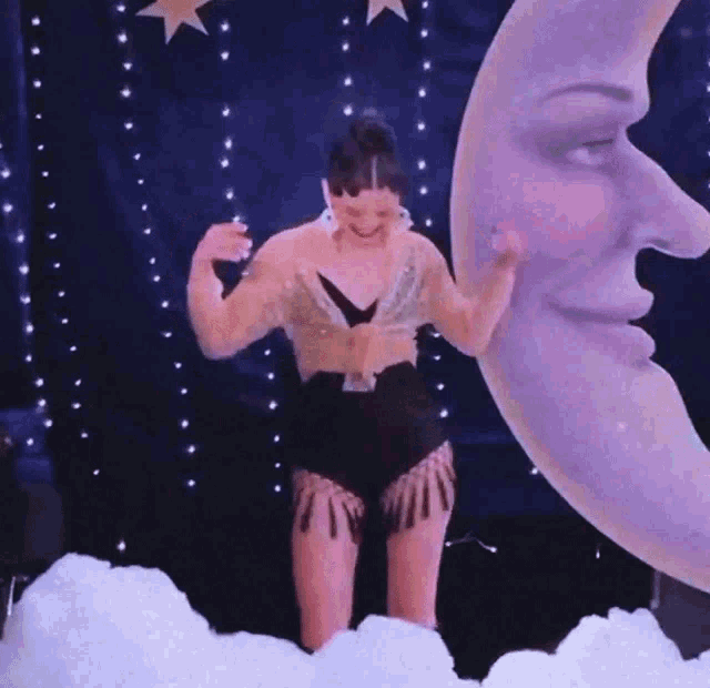 a woman is dancing in front of a large crescent moon