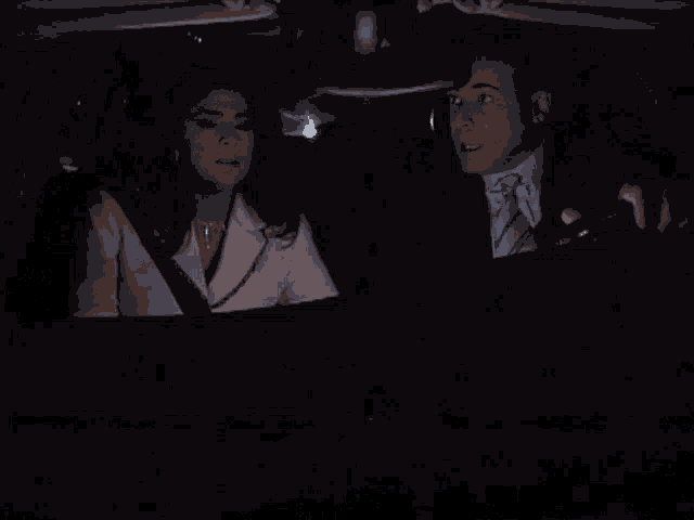 a man and a woman are sitting in the back seat of a car at night