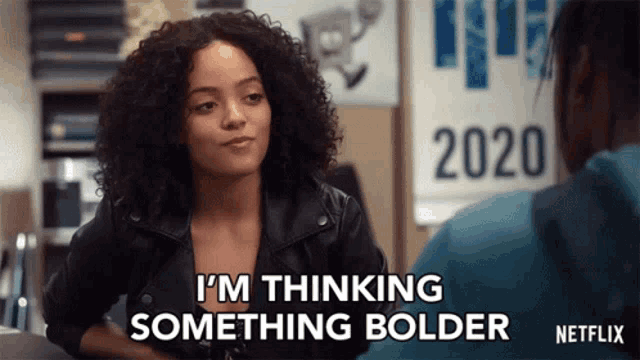 a woman is sitting at a table talking to a man and says `` i 'm thinking something bolder ''