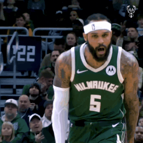 a basketball player for the milwaukee bucks stands in front of the crowd