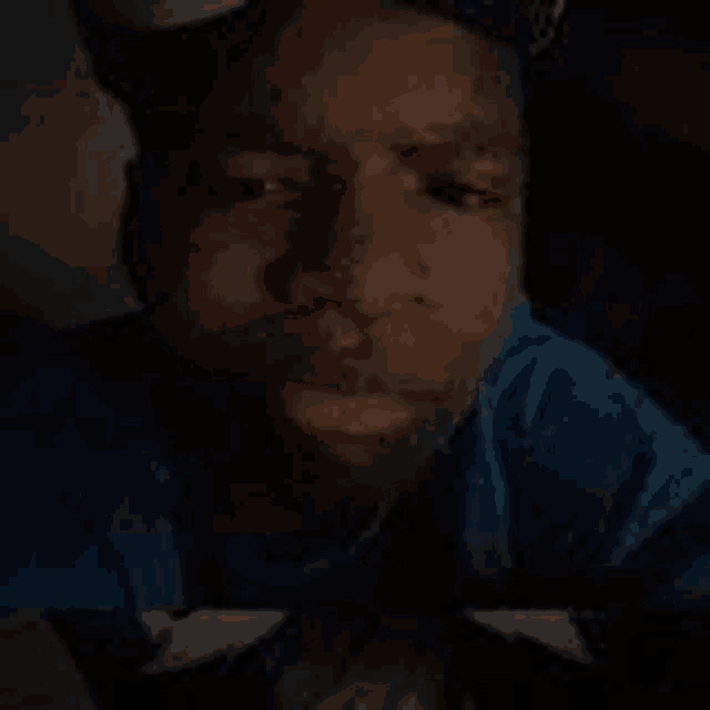 a close up of a man 's face in a dark room looking at something .