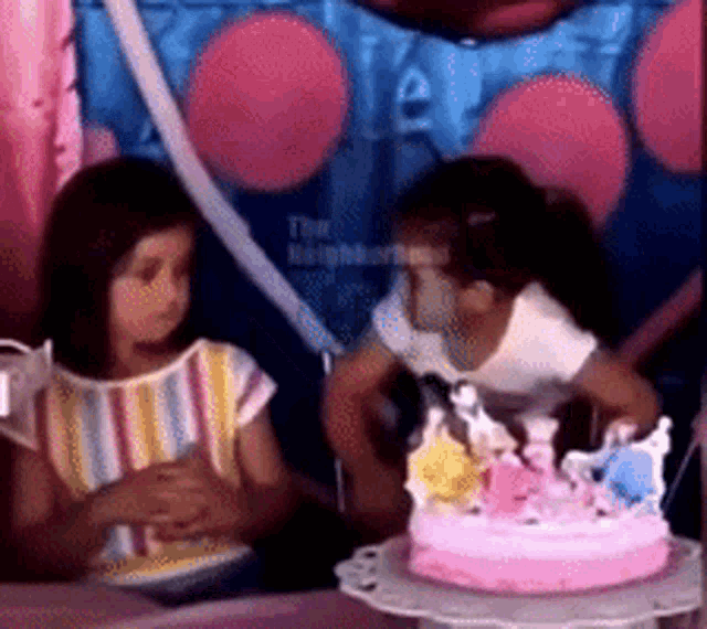 a little girl blows out a candle on a cake with princesses on it