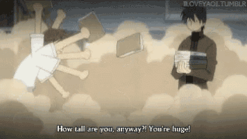 a man holding a stack of books is standing next to a woman laying on the ground .