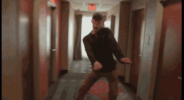 a man in a hat is dancing in a hallway