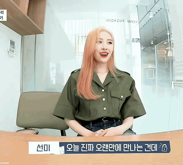 a woman with red hair is sitting at a desk with a sign that says ' a ' on it