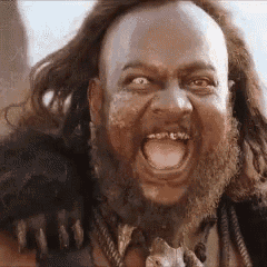 a man with a beard and long hair is making a funny face with his tongue out .