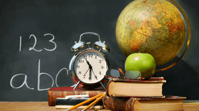 an alarm clock sits on top of a stack of books in front of a blackboard that says 123 abc