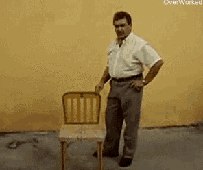 a man standing next to a chair that says " fuck this " on the bottom
