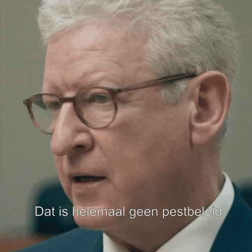 a man wearing glasses and a suit says dat is helemaal geen pestbeeld