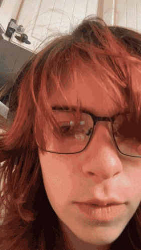 a close up of a person 's face with glasses and red hair