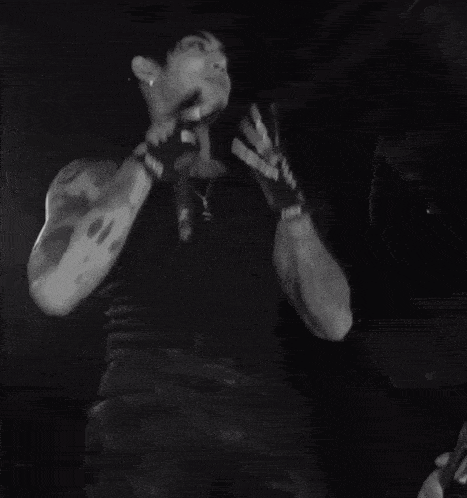 a black and white photo of a man wearing skeleton gloves that say hate