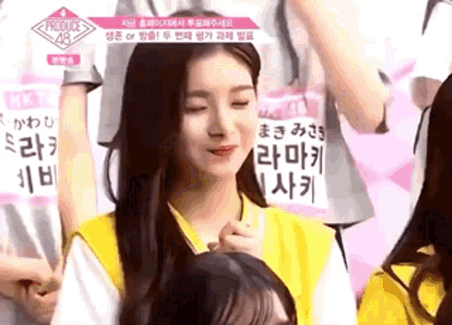 a girl in a yellow vest is sitting in front of a sign that says produce 48 .
