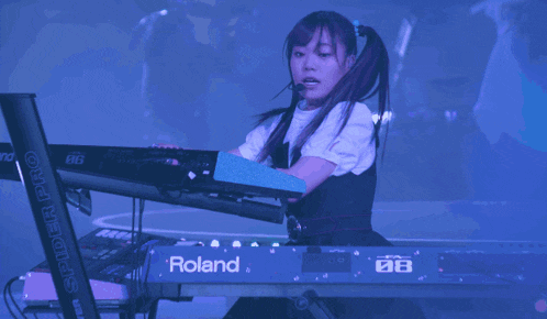 a girl playing a keyboard that says roland on the front