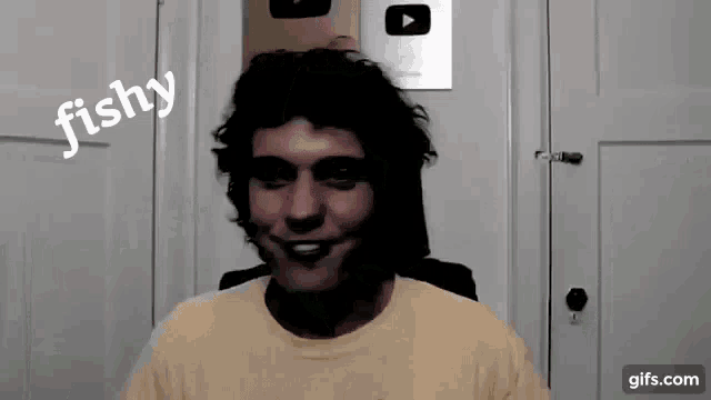 a man in a yellow shirt is smiling in front of a door with the word fishy on it .