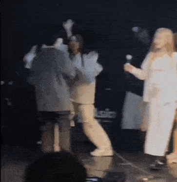 a group of people are dancing on a stage in front of a crowd .