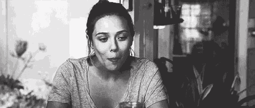 a woman is sitting at a table drinking a glass of water .